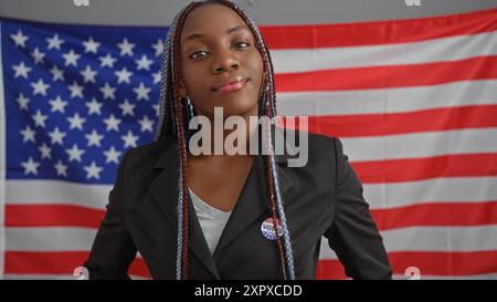 Porträt einer selbstbewussten afroamerikanerin mit Zöpfen, die einen Blazer in einem Büro mit einer US-Flagge trägt. Stockfoto