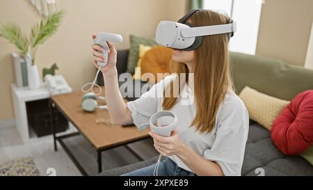 Eine junge Frau genießt Virtual-Reality-Spiele in einem gemütlichen Wohnzimmer. Stockfoto