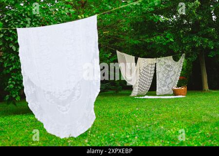Weiße Wäsche auf Wäscheleinen im Garten. Weiße Vorhänge trocknen in der Sonne. Stockfoto