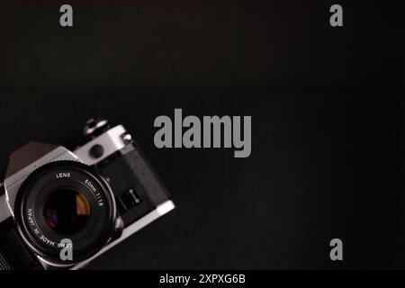 Eine Vintage-Filmkamera in der linken Ecke mit einem großen schwarzen Hintergrund, die die Eleganz alter Fotoausrüstung zeigt. Stockfoto