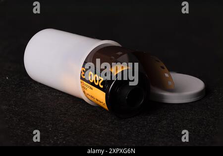 Detaillierte Aufnahme einer 35-mm-Filmrolle vor schwarzem Hintergrund. Ikonische Darstellung traditioneller Fotografie. Stockfoto