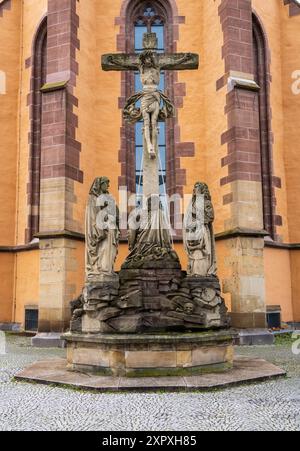 Gedrehte Ansicht einer Kreuzigungsgruppe mit mehreren geschnitzten Figuren vor der gotischen Fassade der Leonhardskirche in Stuttgart, Deutschland. Stockfoto