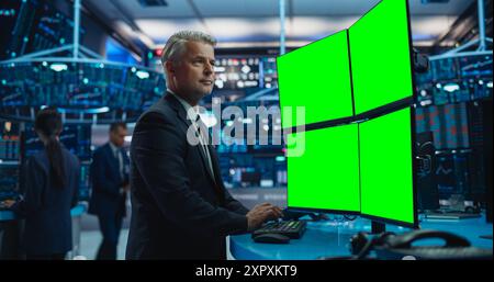 Finanzanalyst mit einem Desktop-Computer mit Multi-Monitor-Workstation mit grünem Bildschirm-Chromakey auf dem Display. Händler, der in einem Börsengeschäft arbeitet und sich Finanzberichte ansieht. Stockfoto