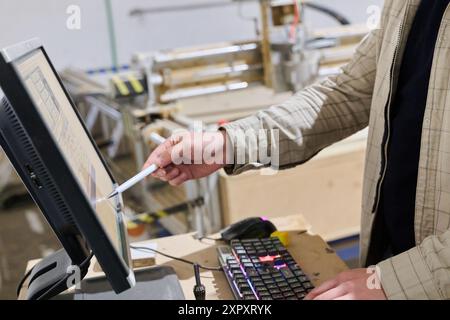 Bediener, der Koordinaten auf dem Computer für die CNC-Maschine eingibt, um Holzstücke präzise zu schneiden Stockfoto