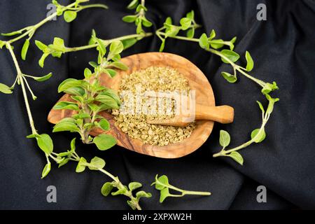 Wildes Origanum, wildes Marjoram (Origanum vulgare), frischer Oregano und gerieben auf einem Holzteller Stockfoto