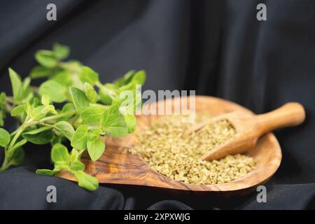 Wildes Origanum, wildes Marjoram (Origanum vulgare), frischer Oregano und gerieben auf einem Holzteller Stockfoto