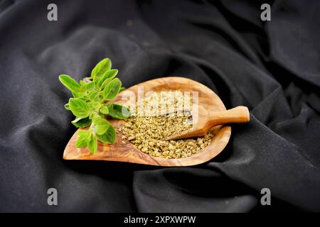 Wildes Origanum, wildes Marjoram (Origanum vulgare), frischer Oregano und gerieben auf einem Holzteller Stockfoto