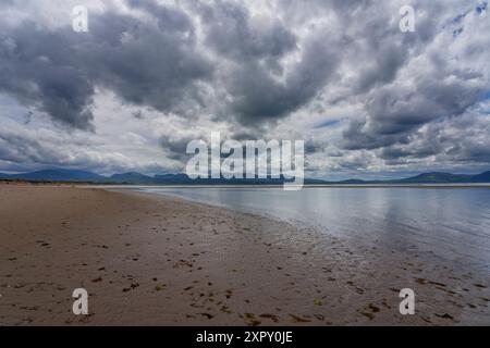 Dunkle Regenwolken über einem einsamen Strand von Llanddwyn, Anglesey, Wales. Stockfoto