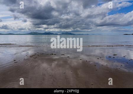 Dunkle Wolken ziehen über den Strand von Llanddwyn, Anglesey, von den fernen Bergen von Snowdonia. Stockfoto