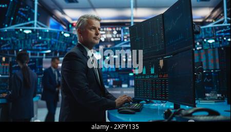 Finanzanalyst mit einem Desktop-Computer mit Multi-Monitor Workstation mit Echtzeit-Diagrammen, Finanzberichten und Marktdiagrammen. Händler, der in einem modernen Börsengeschäft arbeitet Stockfoto