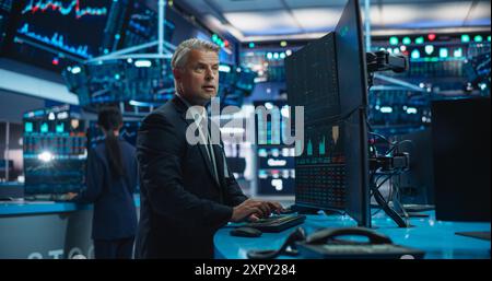Finanzanalyst mit Desktop-Computer und Multi-Monitor-Workstation mit Echtzeit-Diagrammen, Finanzberichten und Marktdiagrammen. Händler, der in einem modernen Börsengeschäft arbeitet Stockfoto