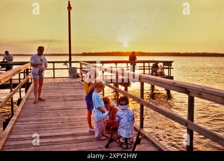 Gruppe von Kindern am Angelpier bei Sonnenuntergang, Fort Parker Lake, Fort Parker State Park, Prairies and Lakes Region, Texas, USA Stockfoto