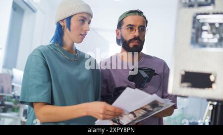 Junge kaukasische weibliche und männliche Kameramann*innen aus dem Nahen Osten berichten über Ein Drehbuch Einer Kamera auf Einem modernen Filmset und zeigen Teamwork in der Videoproduktion für Eine Dokumentarfilm- oder Fernsehshow. Stockfoto