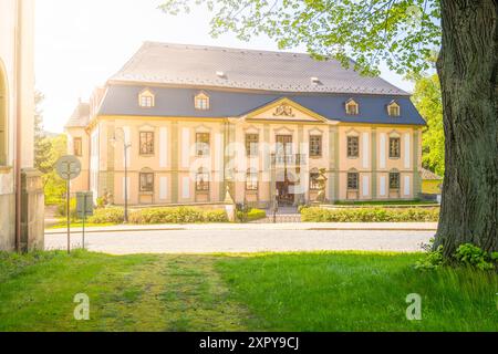 Ein sonniger Blick auf das kleine barocke Schloss Potstejn in Tschechien mit seiner gelben Fassade und grünen Bäumen. Stockfoto