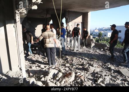 Palästinenser inspizieren das Gebäude, während Feuerwehrleute das Feuer unter Kontrolle nehmen, nachdem die israelische Armee das Haus angegriffen hatte. Palästinenser inspizieren das Gebäude, während Feuerwehrleute das Feuer unter Kontrolle nehmen, nachdem die israelische Armee das Haus der palästinensischen Familie von Momen Masalema angegriffen und es in der Stadt vollständig zerstört hatte Dura, Hebron, Westbank am 08. August 2024. Foto: Mamoun Wazwaz apaimages Hebron Westbank palästinensisches Gebiet 080824 Hebron MW 0019 Copyright: XapaimagesxMamounxWazwazxxapaimagesx Stockfoto