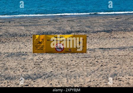 Ein gelbes RNLI-Rettungsschild, das die Menschen warnt, nicht in dieser Gegend zu schwimmen, am Exmouth Beach, Devon. Stockfoto