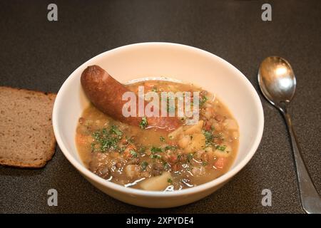 Linsensuppe mit Wurst in einer Schüssel mit Brot an der Seite Stockfoto