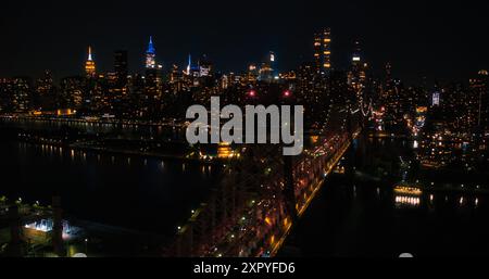 Hubschrauberfoto über Ed Koch Queensboro Bridge mit Manhattan Wolkenkratzern. Wunderschöne Aufnahmen am späten Abend mit Blick auf die Bürogebäude der Upper East Side bei Nacht Stockfoto