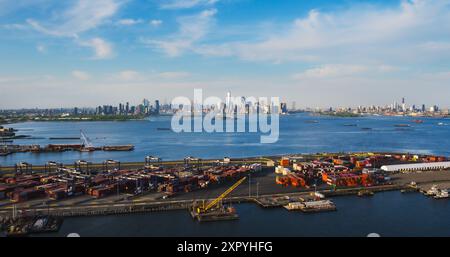 Blick aus der Vogelperspektive auf die Architektur von Manhattan. Panorama von New York City und Jersey City von einem Hubschrauber aus mit Bürogebäuden und Wolkenkratzern. Die Kamera fliegt über einen Hafenbereich mit Versandcontainern Stockfoto