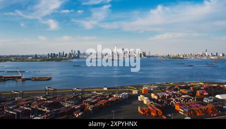 Blick aus der Vogelperspektive auf die Architektur von Manhattan. Panorama von New York City und Jersey City von einem Hubschrauber aus mit Bürogebäuden und Wolkenkratzern. Die Kamera fliegt über einen Hafenbereich mit Versandcontainern Stockfoto