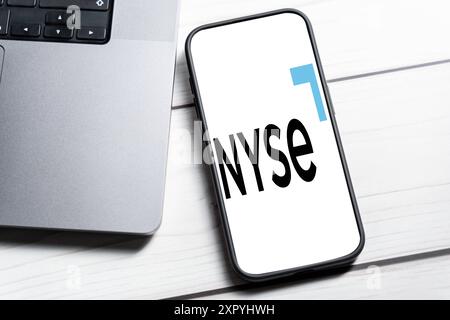 8. August 2024: Ein Smartphone zeigt das Logo der New Yorker Börse NYSE neben einem Laptop auf einem Tisch. FOTOMONTAGE *** ein Smartphone zeigt das Logo der New York Stock Exchange NYSE, neben einem Laptop auf einem Tisch. FOTOMONTAGE Stockfoto