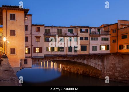 Fesselnder Blick auf die Ponte Vecchio bei Dämmerung über den Fluss Arno in Florenz, Italien, eine historische Brücke mit bezaubernden alten Häusern und Geschäften. Stockfoto