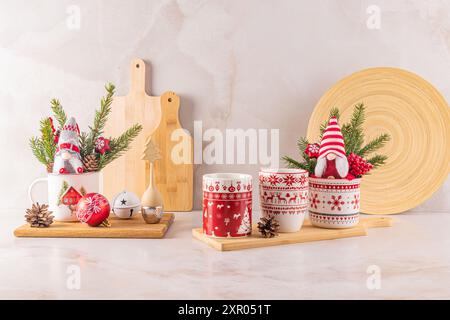 Zwei stilvolle weiße Keramikbecher mit rotem Weihnachtsschmuck in einer festlichen Komposition von Hausdekorationen für die Feiertage. Vorderansicht. Stockfoto