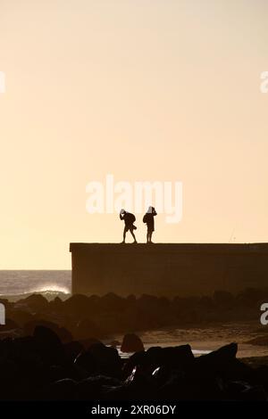 Zwei Personen auf einem windigen Pier bei Sonnenuntergang auf Gran Canaria, den Kanarischen Inseln, Spanien Stockfoto