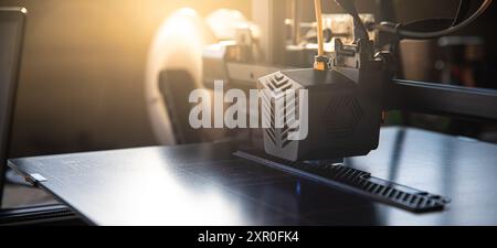 3D-Drucker in Arbeit mit sichtbarem Leerraum links zum Hinzufügen von Text. Sonnenlicht erzeugt dynamische Beleuchtung und unterstreicht den modernen 3D-Druck Stockfoto