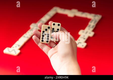 Domino-Spieler mit rechteckigen Acrylstücken. Brettspiel. Roter Hintergrund. Stockfoto