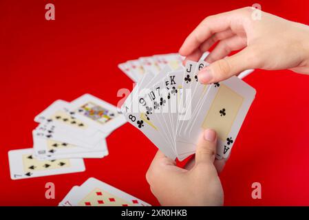 Brettspiel. Karten spielen. Pokerkarten in einer Hand eines jungen Mannes. Isoliert auf rotem Hintergrund. Stockfoto