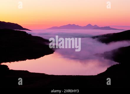 Die Inseln Rum und Eigg in den Inneren Hebriden, von der Ardnamurchan-Halbinsel aus durch den Nebel des Meeres bei Sonnenuntergang, Argyll, Schottland, Mai Stockfoto