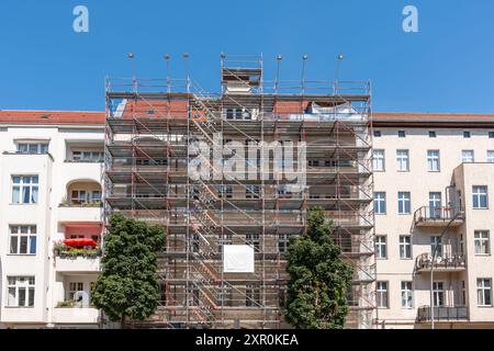 Ein Gebäude mit Gerüsten und einer Leiter an der Seite. Das Gebäude ist hoch und hat viele Fenster Stockfoto