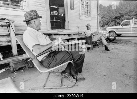 Mazedonien, Arkansas, Vereinigte Staaten – 23. Juni 2024: Horizontaler Schuss von zwei Männern, die vor einem alten Laden aus den 1970er Jahren sitzen und sich unterhalten. Stockfoto