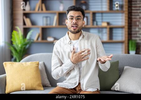 Kranker männlicher Patient mit Telefon für Videoanruf während der Online-Konsultation mit dem Arzt, klagt über Brustschmerzen. Mann sucht medizinischen Rat von zu Hause in ungezwungener Umgebung. Stockfoto