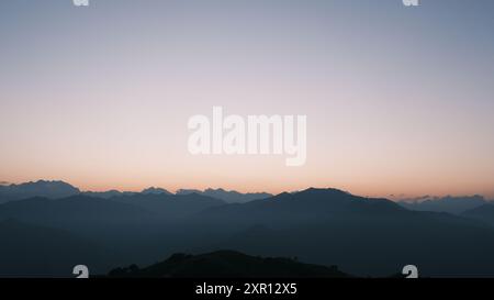 Eine ruhige Berglandschaft bei Sonnenuntergang mit klarem Himmel und Silhouetten von Gipfeln Stockfoto