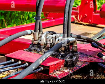 Nahaufnahme von Hydraulikschläuchen und -Armaturen an Landmaschinen mit detaillierten Komponenten und Verbindungen. Stockfoto