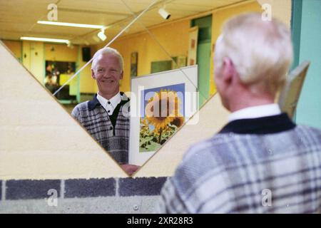Mann mit Sonnenblumenmalerei neben einem Spiegel, Whizgle Dutch News: Historische Bilder für die Zukunft. Erkunden Sie die Vergangenheit der Niederlande mit modernen Perspektiven durch Bilder von niederländischen Agenturen. Verbinden der Ereignisse von gestern mit den Erkenntnissen von morgen. Begeben Sie sich auf eine zeitlose Reise mit Geschichten, die unsere Zukunft prägen. Stockfoto