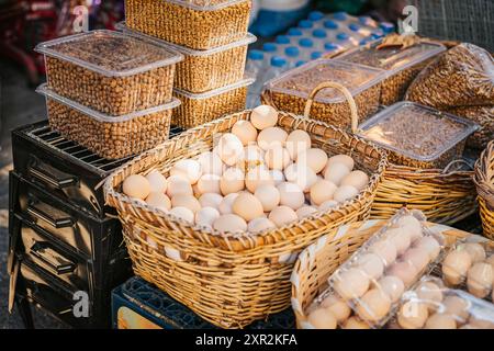 Frische Eier und Nüsse in Korbkörben auf einem geschäftigen Markt am Morgen Stockfoto