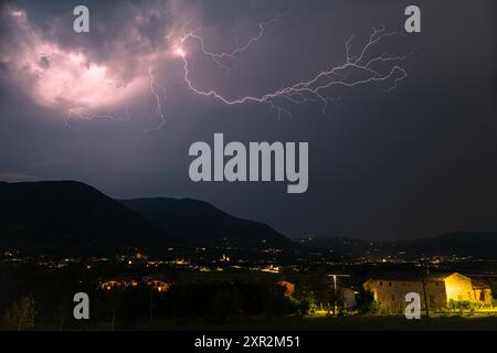 Ein rosafarbener Blitz taucht aus einem schweren Gewitter über den Bergen in der Nähe des Gardasees auf Stockfoto