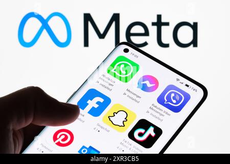 Nahaufnahme eines Smartphone-Bildschirms mit verschiedenen Social Media- und Kommunikations-Apps mit Meta-Logo im Hintergrund, das die Vielfalt der Apps zeigt Stockfoto