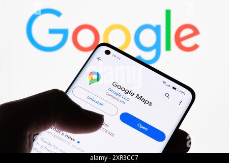 Nahaufnahme eines Smartphone-Bildschirms, auf dem die Google Maps-App mit dem Google-Logo im Hintergrund angezeigt wird, um die Verbindung zwischen Google Maps und Goo zu veranschaulichen Stockfoto