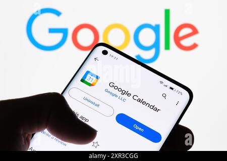 Nahaufnahme eines Smartphone-Bildschirms, auf dem die Google Kalender-App mit dem Google-Logo im Hintergrund angezeigt wird und der Link zwischen Google Kalender und Google angezeigt wird Stockfoto