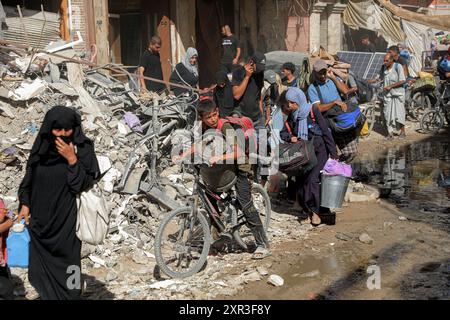 Gaza. August 2024. Am 8. August 2024 fliehen Menschen aus den östlichen Bezirken der Stadt Khan Younis im südlichen Gazastreifen. Nach einer neuen Evakuierungsanordnung der israelischen Behörden sagten UN-humanitäre Helfer am Donnerstag, dass ihre Partner Tausende von Gazern erneut aus Teilen des Gebiets Khan Younis im Westen in Richtung Al Mawasi flohen. Quelle: Rizek Abdeljawad/Xinhua/Alamy Live News Stockfoto