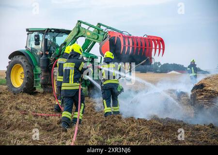 240808Strohballenbrand News ID: EN 2024-08-08-08, Strohballenbrand beschäftigt Einsatzkräfte Landwirte unterstützen Brandbekämpfung Gornau. Am Donnerstagabend gegen 19:50 Uhr ist auf einem Feld an der Eisenstraße ein Strohballenbrand ausgebrochen. Wie die Feuerwehr berichtet, standen bei Ankunft der ersten Kräfte, 30 Strohballen in Vollbrand. Umgehend begann man mit der Brandbekämpfung. Zeitgleich verhinderten die Kameraden eine weitere Ausbreitung des Brandes. Unterstützt werden die Löschmaßnahmen von Landwirten. Diese pflügten das Stoppelfeld um und nahmen so dem Feuer das brennbare Material. Au Stockfoto