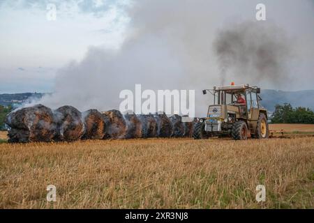 240808Strohballenbrand News ID: EN 2024-08-08-08, Strohballenbrand beschäftigt Einsatzkräfte Landwirte unterstützen Brandbekämpfung Gornau. Am Donnerstagabend gegen 19:50 Uhr ist auf einem Feld an der Eisenstraße ein Strohballenbrand ausgebrochen. Wie die Feuerwehr berichtet, standen bei Ankunft der ersten Kräfte, 30 Strohballen in Vollbrand. Umgehend begann man mit der Brandbekämpfung. Zeitgleich verhinderten die Kameraden eine weitere Ausbreitung des Brandes. Unterstützt werden die Löschmaßnahmen von Landwirten. Diese pflügten das Stoppelfeld um und nahmen so dem Feuer das brennbare Material. Au Stockfoto