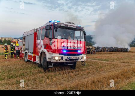 240808Strohballenbrand News ID: EN 2024-08-08-08, Strohballenbrand beschäftigt Einsatzkräfte Landwirte unterstützen Brandbekämpfung Gornau. Am Donnerstagabend gegen 19:50 Uhr ist auf einem Feld an der Eisenstraße ein Strohballenbrand ausgebrochen. Wie die Feuerwehr berichtet, standen bei Ankunft der ersten Kräfte, 30 Strohballen in Vollbrand. Umgehend begann man mit der Brandbekämpfung. Zeitgleich verhinderten die Kameraden eine weitere Ausbreitung des Brandes. Unterstützt werden die Löschmaßnahmen von Landwirten. Diese pflügten das Stoppelfeld um und nahmen so dem Feuer das brennbare Material. Au Stockfoto