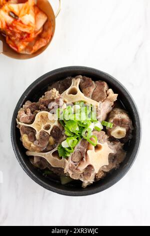 Koreanische Oxtail-Suppe von oben oder Kkori Gomtang, serviert mit Napa Cabbage Kimchi Stockfoto