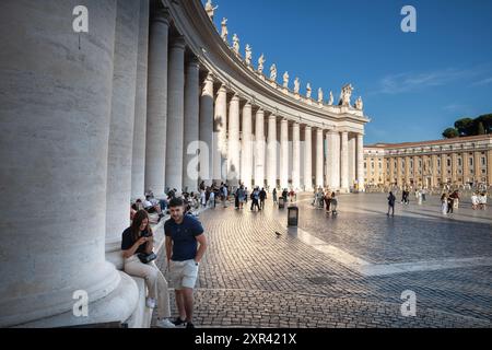 Dieses Bild zeigt Touristen, die an den ikonischen Säulen des Petersplatzes im Vatikan stehen. Die Szene beleuchtet die historische und kulturelle bedeutung Stockfoto