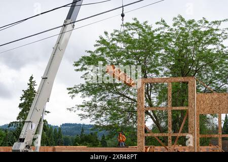 Wohnhausbau, Auslegerkran heben Holzlieferungen, Holzträger, zum wartenden Arbeiter Stockfoto